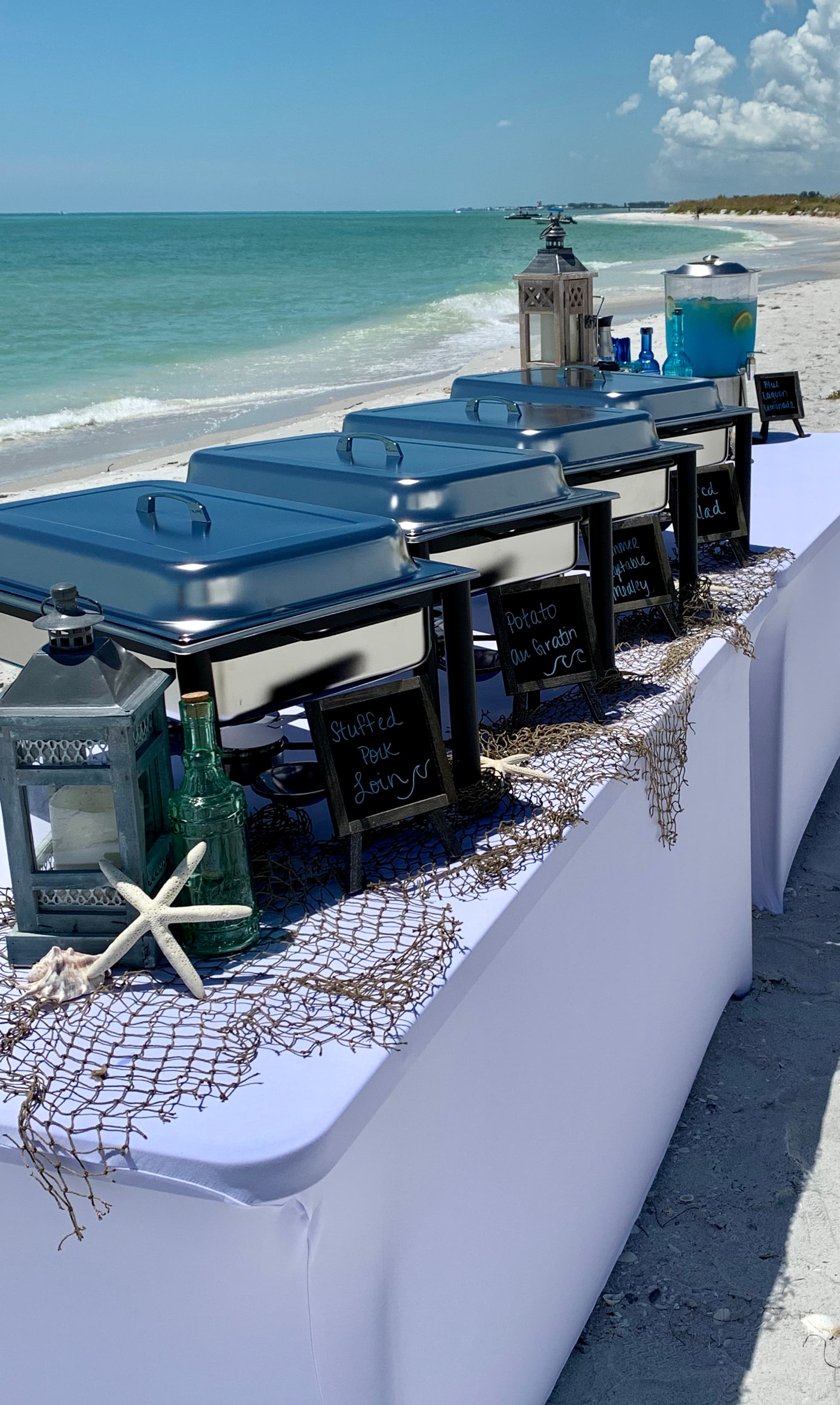 Blue Water Catering chafing dishes lined up on the beach